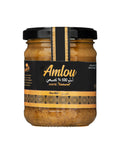 A glass jar of Amlou spread with a black lid and a black label featuring gold text and patterns, set against a plain white background.
