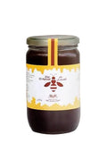 A jar of Dar El Ansar honey shown against a blurred kitchen background with Arabic promotional text above and a small corn cob prop on the right.