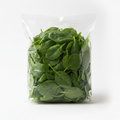 A clear plastic bag filled with fresh green spinach leaves, photographed on a clean white background.
