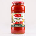 A glass jar of apis Tomate Frito Casero tomato sauce, showing the red sauce inside, with a white and green label and a red metal lid, set against a plain white background.