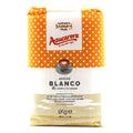 A 1 kg bag of Azucarera brand white sugar, featuring a bright orange and white polka dot pattern on the top half, a white center label with the red 'Azucarera' logo, and a light beige textured bottom half.