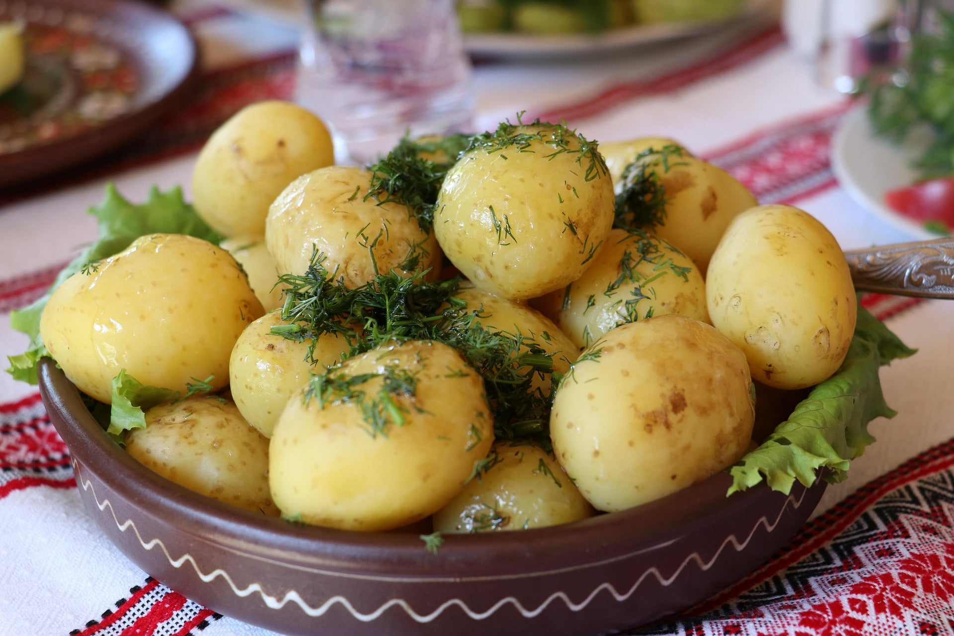 Platter of boiled potatoes with herbs on a decorative tablecloth