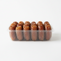 A clear plastic clamshell container filled with brown dates, photographed on a clean white background.