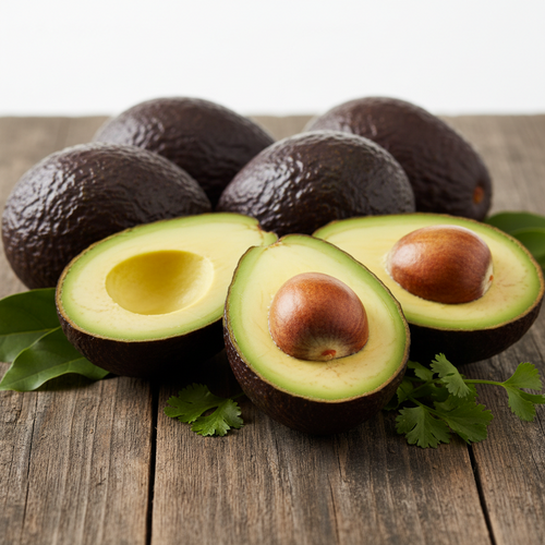Several avocados on a rustic wooden surface, with two halves cut open in front to show the green flesh and large brown pit, garnished with a few green leaves.