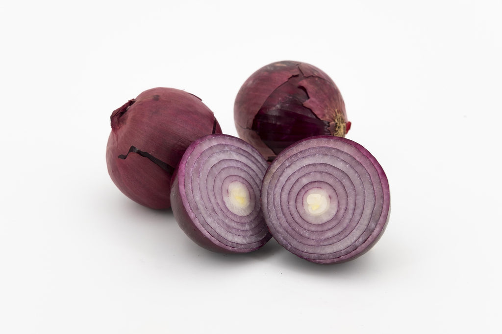 Three red onions on a white background, with two cut in half to show the layered purple-red onion rings and pale centers.