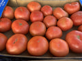 A close-up view of many red tomatoes packed inside a cardboard shipping box.