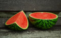 Halved watermelon on a wooden surface with a dark background