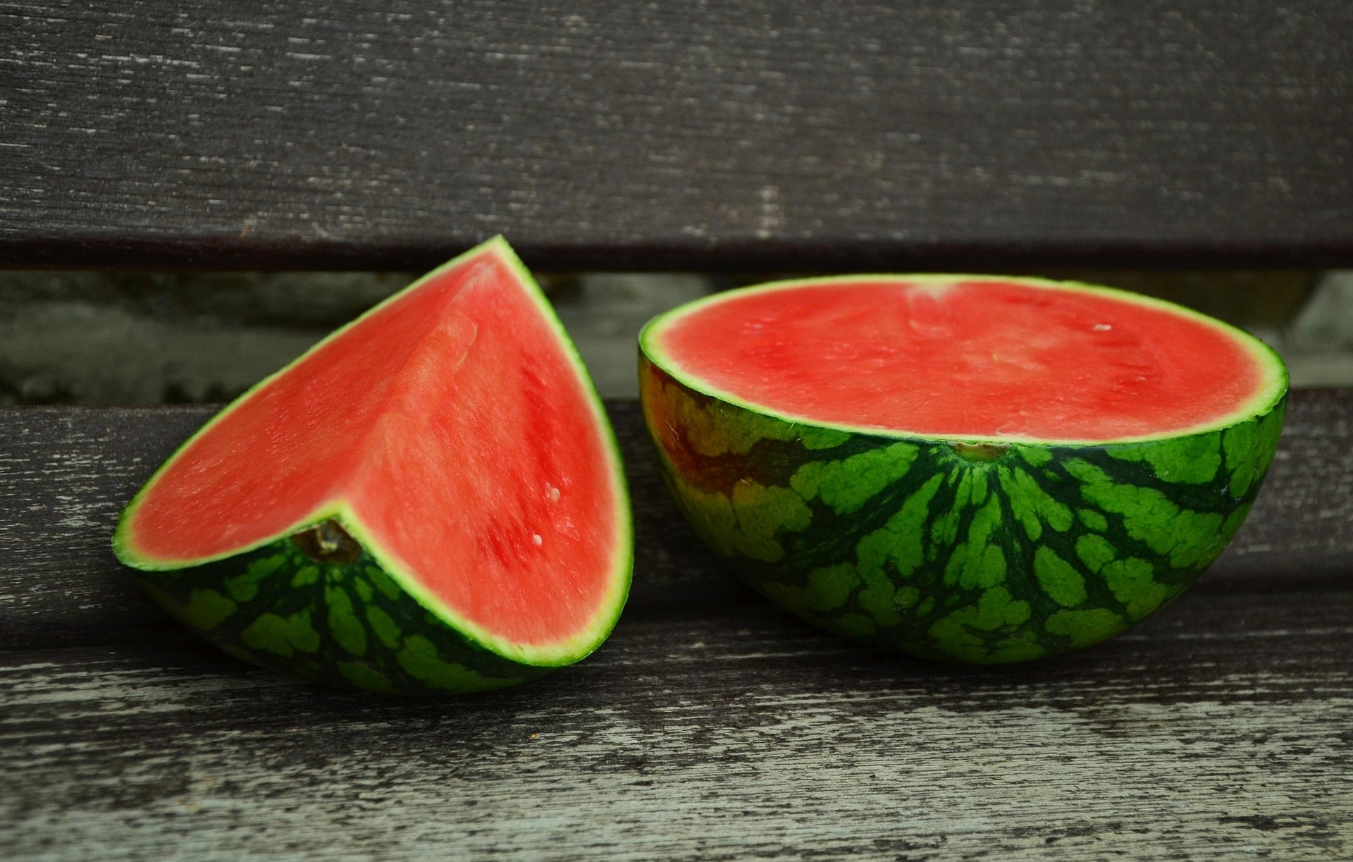 Halved watermelon on a wooden surface with a dark background
