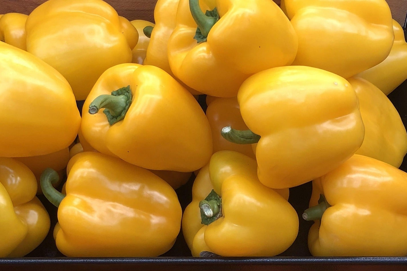 Yellow bell peppers displayed in wooden crates